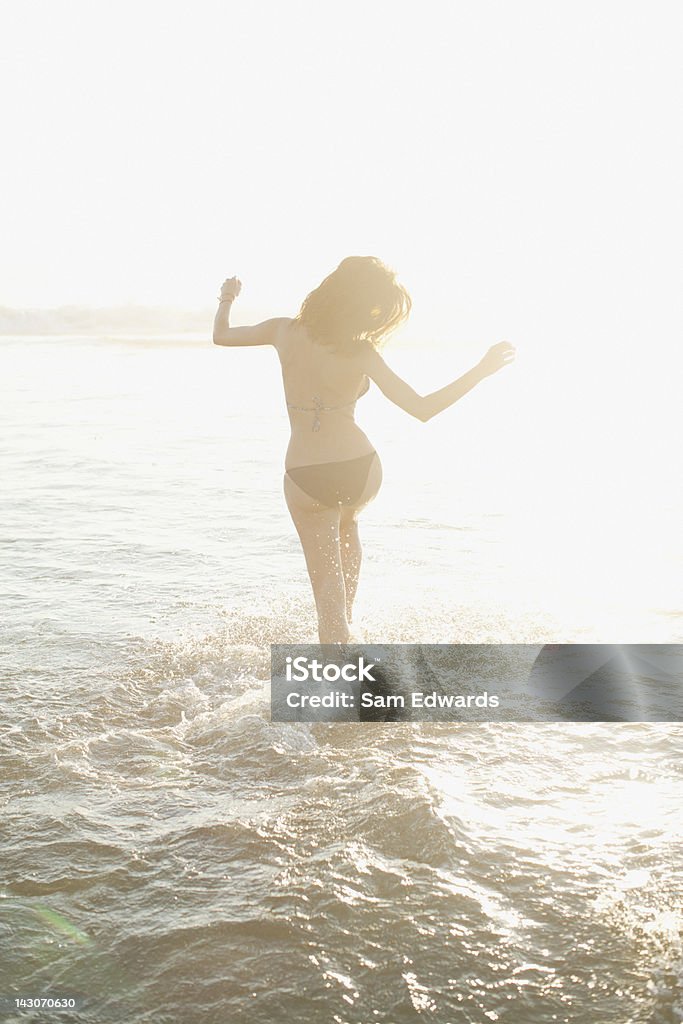 Donna camminare in onde sulla spiaggia - Foto stock royalty-free di Sensualità