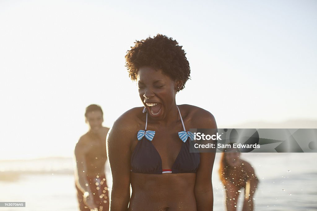 Amici che giocano in onde sulla spiaggia - Foto stock royalty-free di Spiaggia