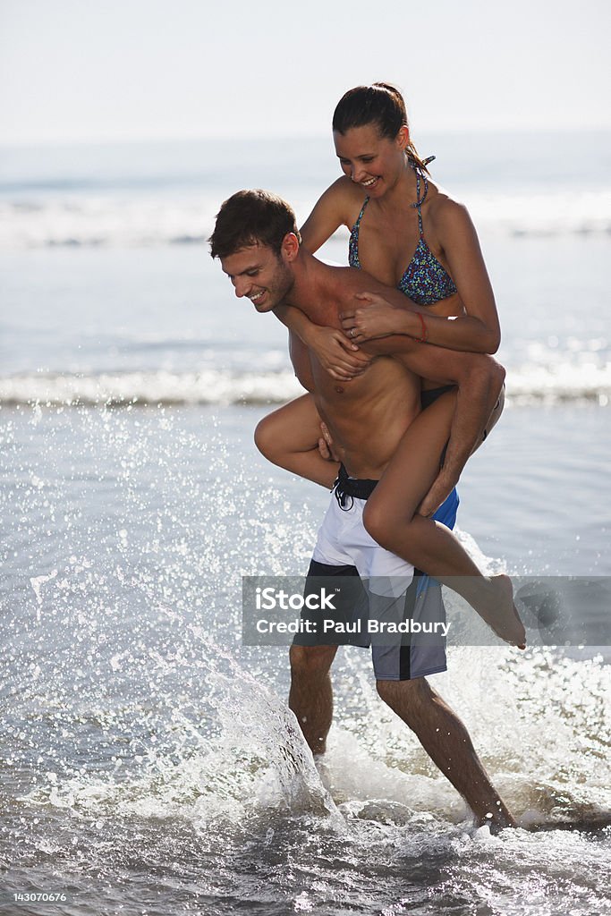 Pareja jugando en las olas en la playa - Foto de stock de Juguetón libre de derechos