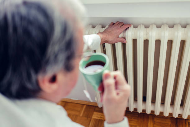 istock Dissatisfied senior men having problem with central heating, sitting on sofa at home, freezing, drinking hot tea trying to warm up. Energy crisis concept. 1430708331