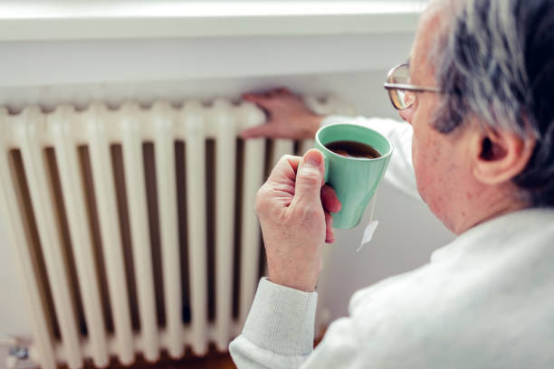 istock Dissatisfied senior men having problem with central heating, sitting on sofa at home, freezing, drinking hot tea trying to warm up. Energy crisis concept. 1430708357