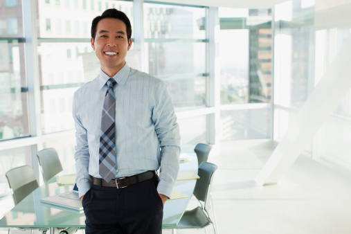 Portrait of happy mature Asian business man standing with arms crossed at the office work