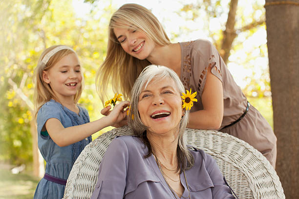 trois générations de femmes jouant à l'extérieur - mother family vertical flower photos et images de collection