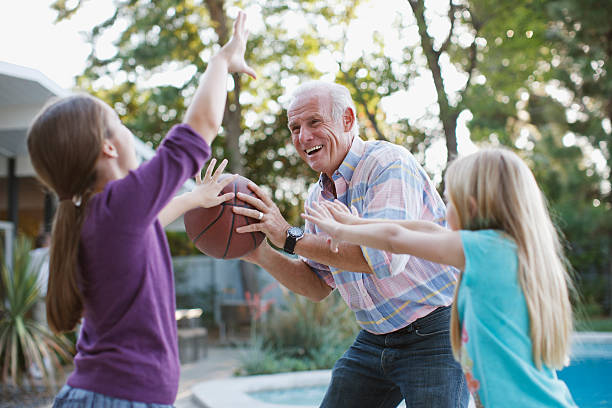 anziani uomo giocando a basket con granddaughters - termine sportivo foto e immagini stock