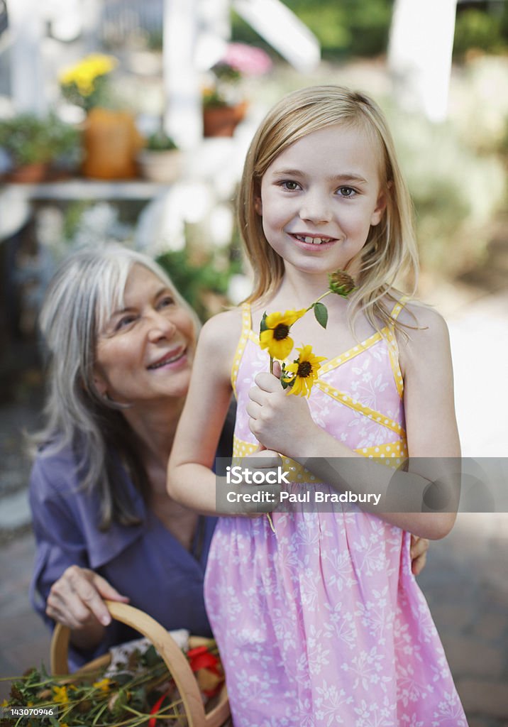 Donna anziana e la nipote prelievo fiori - Foto stock royalty-free di 55-59 anni