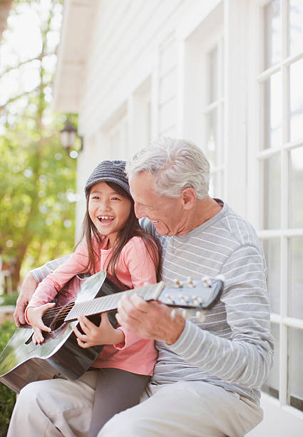 hombre mayor envenenado y granddaughter tocando la guitarra - grandchild grandparent child senior adult fotografías e imágenes de stock