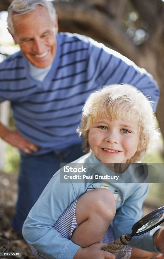 Anziani uomo e nipote utilizzando la lente d'ingrandimento - Foto stock royalty-free di 4-5 anni
