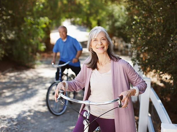 sonriente pareja de ancianos montar bicicletas - senior adult healthy lifestyle exercising cycling fotografías e imágenes de stock