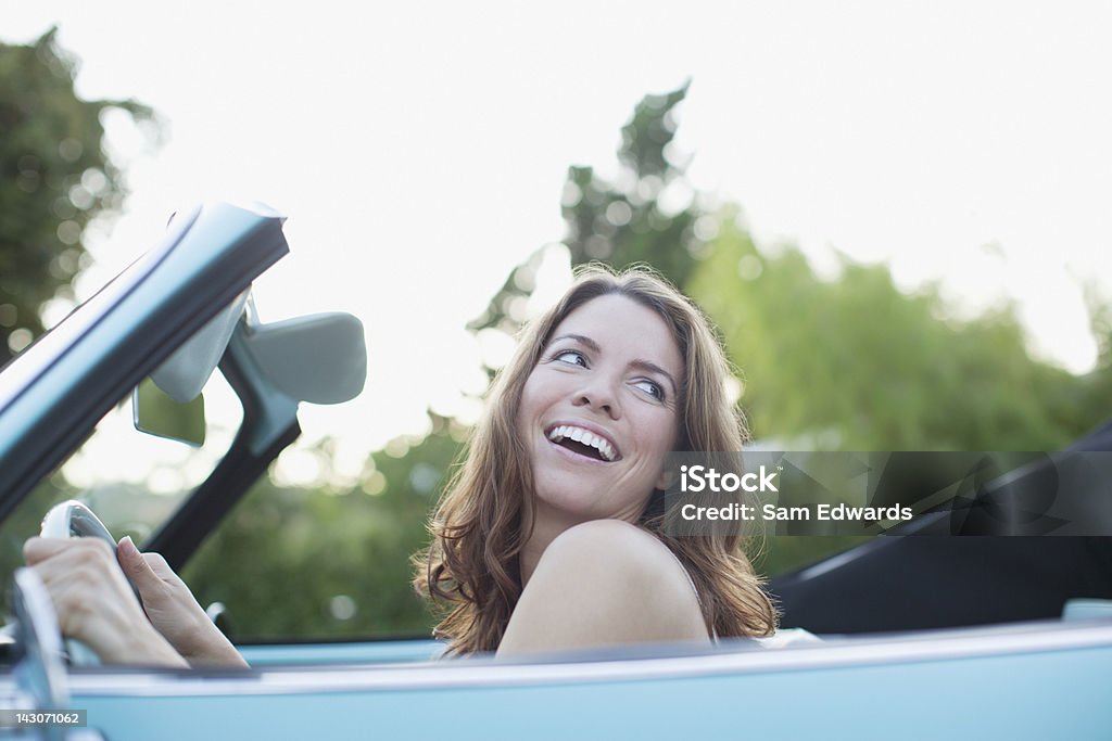 Donna sorridente seduto in Auto convertibile - Foto stock royalty-free di Donne