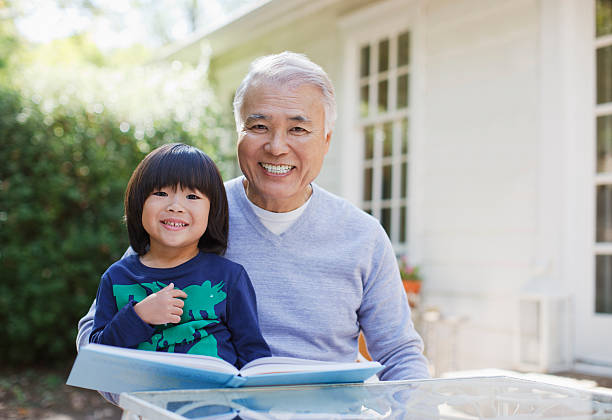hombre mayor envenenado lectura con nieto al aire libre - grandparent adult smiling looking at camera fotografías e imágenes de stock