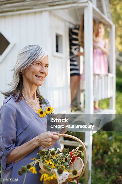 Mujer De Edad Avanzada Luego Flores Al Aire Libre Foto de stock y más banco de imágenes de Abuela - Abuela, Hija, Madre