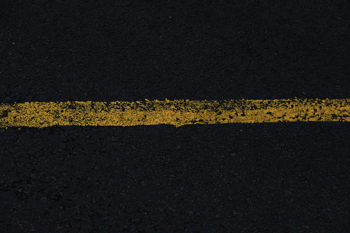 Texture of the rain black road with yellow white painted lanes and cracks