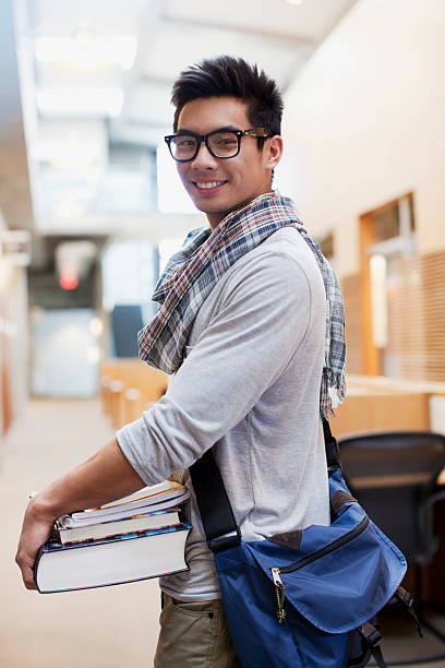 Student carrying books in school hallway  asian adult student stock pictures, royalty-free photos & images