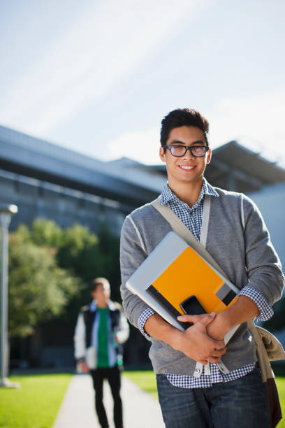 étudiant transportant des dossiers en plein air - learning male studying smiling photos et images de collection