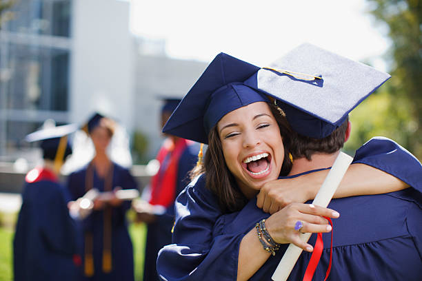 lächelnd absolventen umarmen im freien - schul oder uniabschluss stock-fotos und bilder