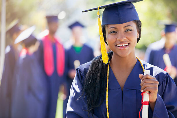 smiling graduate holding diploma - toga stockfoto's en -beelden