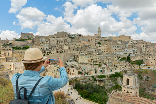 Young elegant woman tourist in historical Matera town in Italy taking ,