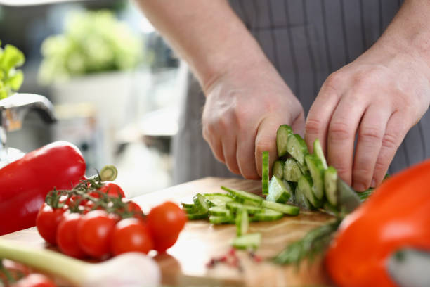 istock Green cucumbers are cut with knife in kitchen 1430716841