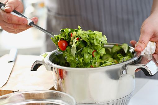 Male chef prepares fresh detox healthy salad on table. Mixing salad in bowl concept