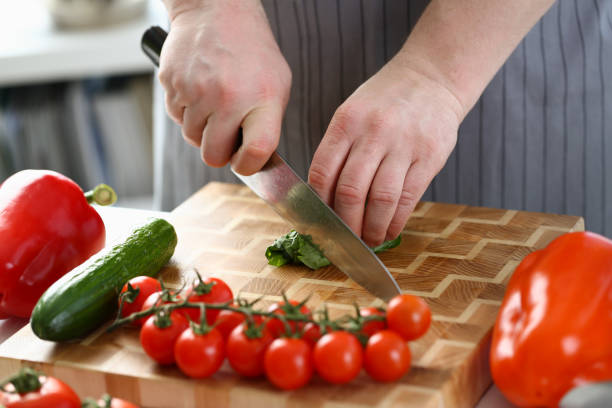istock Chef is preparing salad of spinach cucumbers and tomatoes in kitchen 1430716896