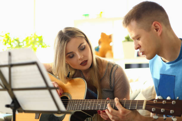 istock Man conducts guitar lessons for woman closeup 1430716907