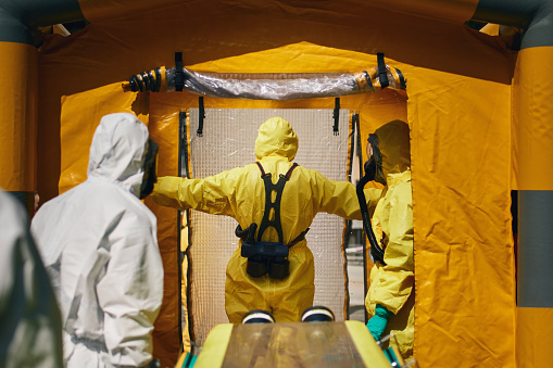 Members of biohazard teams of fire brigade and emergency medical service in protective suits.