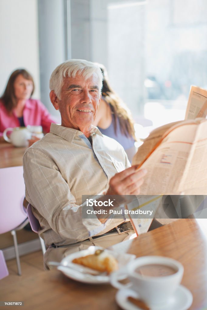 Homme lisant un journal dans le café - Photo de Hommes seniors libre de droits