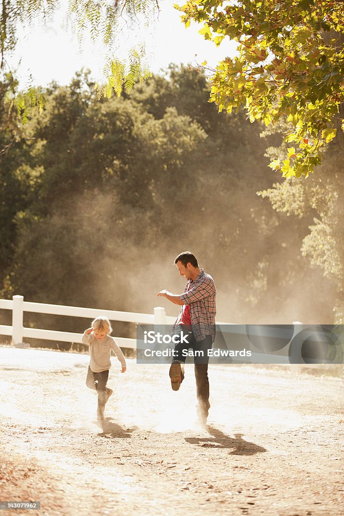 Padre e figlio calciare in polvere su Strada in terra battuta - Foto stock royalty-free di 30-34 anni