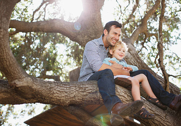 père et son fils se tenant dans tree - mode de vie rural photos et images de collection