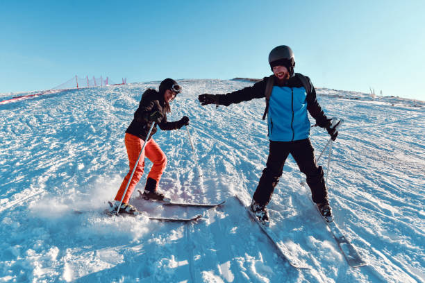 Male And Female Trying To Ski While Holding Hands