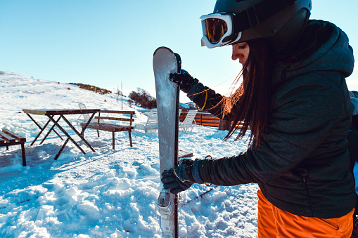 Female Cleaning Snowboard Before Going For A Downhill Ride