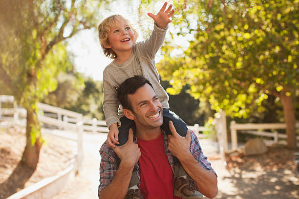 Father carrying son on shoulders  on shoulders stock pictures, royalty-free photos & images