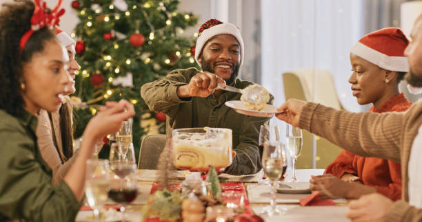 Christmas celebration, dessert and people eating at a dining room table for love, happiness and holiday. Happy family or friends group share cake, food and wine at a party reunion and home dinner stock photo