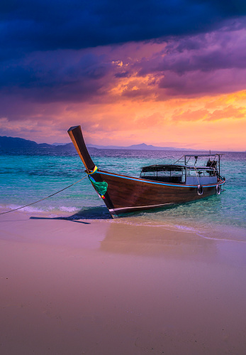 Dramatic sunset over Railay Beach at Krabi, Thailand, with traditional long tail boat in the foreground. Travel concept.