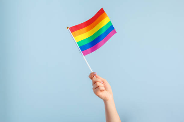Gay flags in women's hand on grey background stock photo
