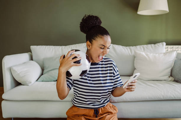 Multiracial woman celebrating a goal and using smart phone