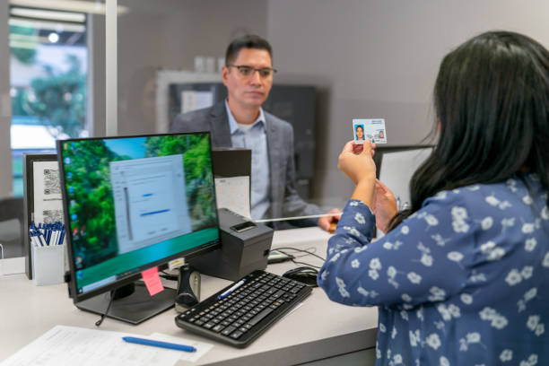 bank teller checking customer's driver's license - cheque fotos stockfoto's en -beelden