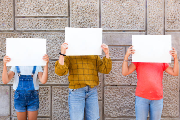 Three girls holding you advertisment in front of them stock photo