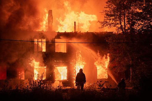 two silhouette of firefighters on housefire background