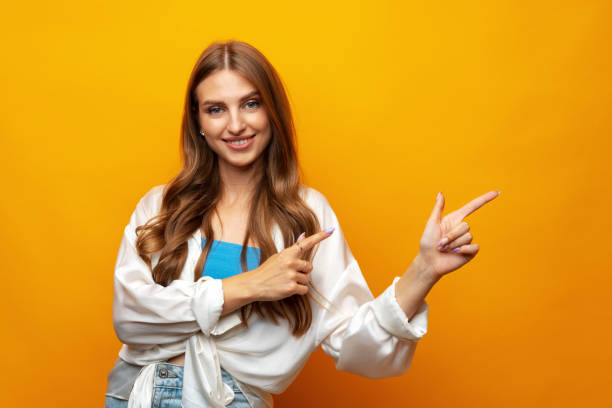 istock Young pretty woman pointing at copy space in studio 1430737736