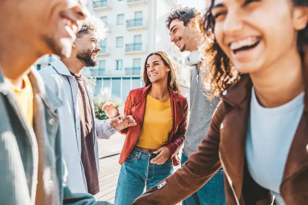 Photo of Happy multiracial friends having fun together walking on city street - Group of young people hanging out in town on a sunny day - University students talking and laugh out loud in college campus