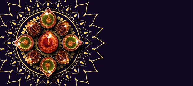 Deepavali Diwali, Hindu Festival of lights celebration. Diya oil lamp lit on traditional black background, top view.