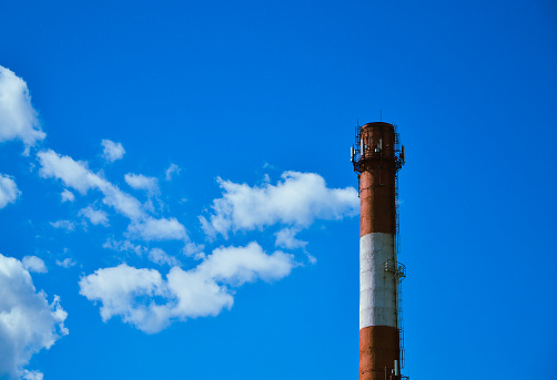 Boiler room chimney against a background of bright blue sky and white clouds