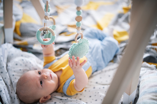 Curious little baby boy playing with wooden sensory tooy at home.