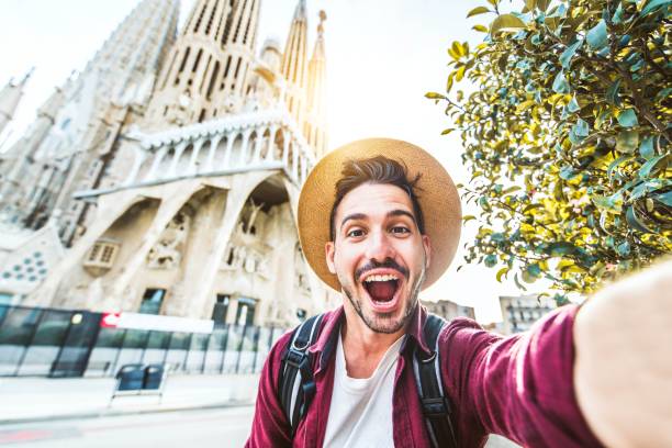 turista feliz visitando la sagrada família, barcelona espanha - homem sorridente tirando uma selfie ao ar livre na rua da cidade - turismo e conceito de férias - mid adult men portrait hat human face - fotografias e filmes do acervo