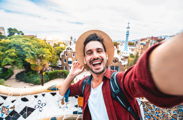 glücklicher tourist macht selfie-selbstporträt mit smartphone im park güell, barcelona, spanien - lächelnder mann im urlaub schaut in die kamera - urlaubs- und reisekonzept - parc guell stock-fotos und bilder