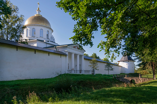 View of the outer wall of the Holy Dormition Pskov-Pechersk Monastery and St. Michael's Cathedral on a sunny summer day, Pechora, Pskov region, Russia