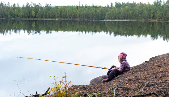 Northern nature of Finland, a child is fishing with a rod in rainy weather, autumn. Close to Lahti