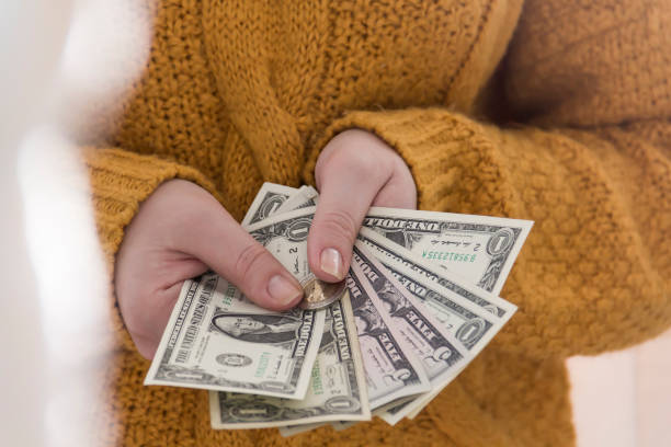 istock Women's hands in a yellow sweater hold small dollar bills. 1430751129