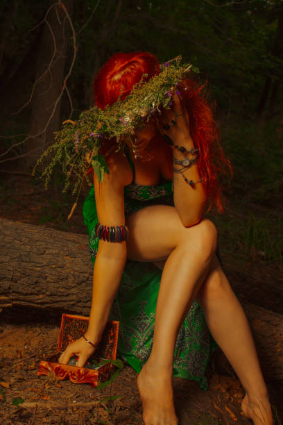 Redhead beautiful lady in green dress posing in the forest